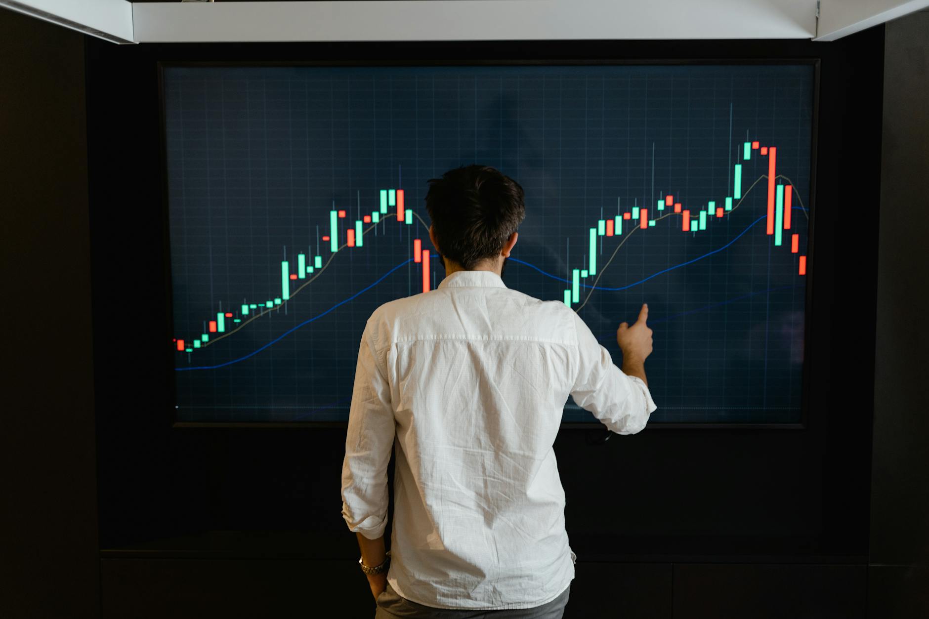 A person analyzing cryptocurrency charts on a laptop with financial news displayed.