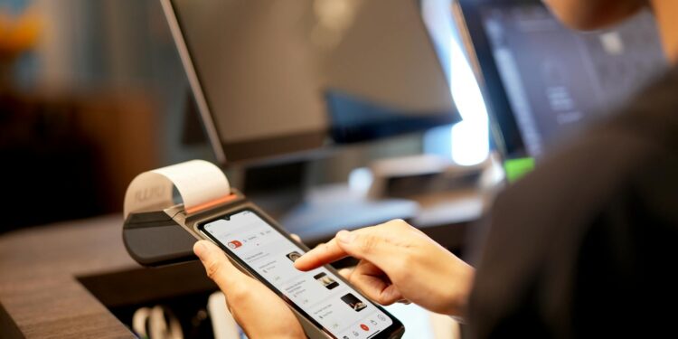 A smartphone displays a Bitcoin payment app with a merchant's payment terminal.