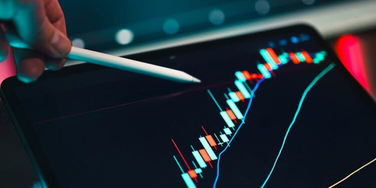 A person analyzes cryptocurrency charts on a computer screen with regulatory documents nearby.