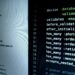 Developers monitoring code with warning signs for malicious Axios packages in a foggy environment.