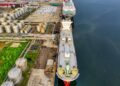 Cargo ships in a busy harbor, symbolizing oil trade and potential regulatory changes.
