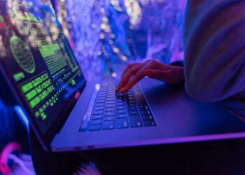 A hacker's hand on a keyboard, symbolizing cyber threats in cryptocurrency phishing attacks.