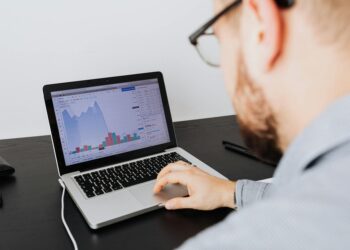 A Vietnamese citizen analyzing cryptocurrency trends on a laptop with graphs and charts.