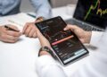 Two professionals discussing cryptocurrencies with charts and data on screens around them.