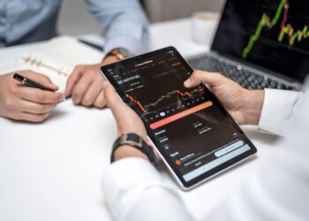 Two professionals discussing cryptocurrencies with charts and data on screens around them.