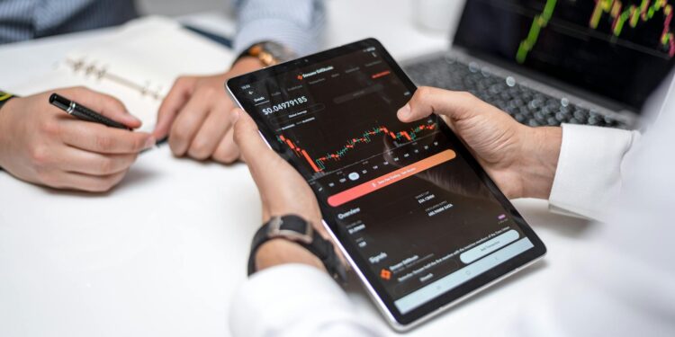 Two professionals discussing cryptocurrencies with charts and data on screens around them.
