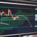 A digital chart showing Bitcoin's price drop below $69,200 with financial graphs in the background.
