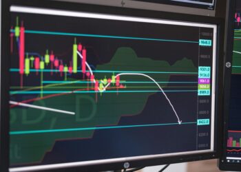 A digital screen displaying cryptocurrency prices and trading charts in a trading room.