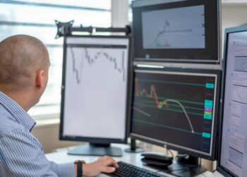 Traders monitor crypto charts on multiple screens with Binance logo in focus.
