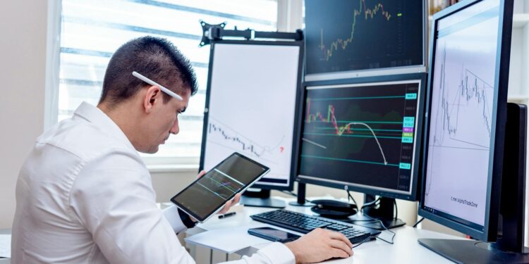 Traders monitoring oil futures on electronic screens in a busy financial trading environment.