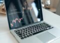 A financial analyst examines cryptocurrency charts on a laptop in a modern office setting.