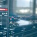 A close-up of a blockchain graphic overlaid with financial data charts and currency symbols.