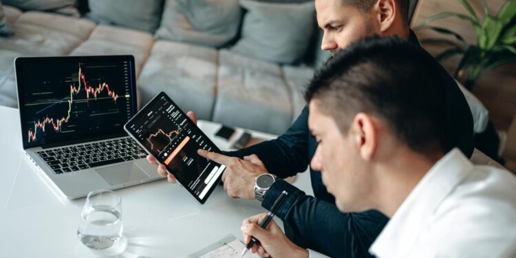 Two professionals discussing blockchain technology with digital charts and graphs in the background.