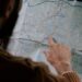 Trump and Iranian officials discussing maritime security over a map of the Strait of Hormuz.