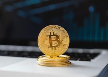 A digital illustration of a bank building with cryptocurrency symbols and coins surrounding it.