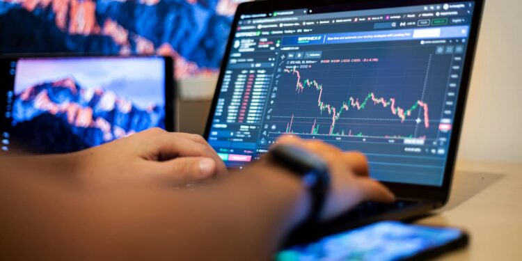 A developer working on a laptop, surrounded by crypto and finance charts on screens.