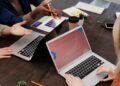 A modern office setting with team members discussing blockchain technology over laptops.