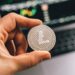 A close-up of a digital currency symbol overlaying a blurred financial market background.