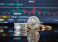Bitcoin coins stacked with a fluctuating stock market graph in the background.