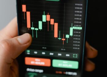 A smartphone displaying the Sora Video App interface with financial graphs in the background.