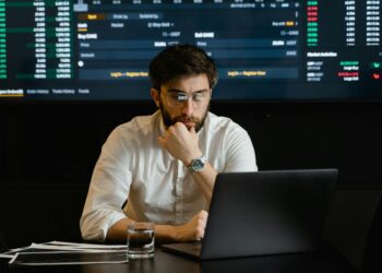 A developer analyzing blockchain data on a laptop with cryptocurrency graphics in the background.