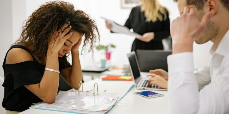Employees in an office looking concerned as news of AI-related layoffs circulates.