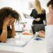 Employees in an office looking concerned as news of AI-related layoffs circulates.