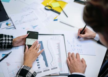 A diverse group of professionals collaborates over blockchain graphics and financial data charts.