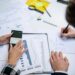 A diverse group of professionals collaborates over blockchain graphics and financial data charts.