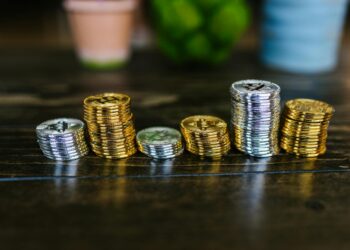 Stacks of Bitcoin coins with a police badge and handcuffs on a table.