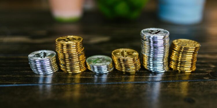 Stacks of Bitcoin coins with a police badge and handcuffs on a table.
