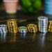 Stacks of Bitcoin coins with a police badge and handcuffs on a table.