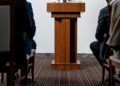 SEC Chair speaking at a podium, discussing crypto regulation and safe harbor for firms.