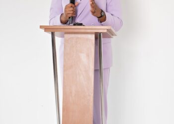 Senator Warren speaking at a podium, addressing concerns about youth crypto banking apps.