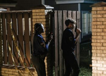 Law enforcement officers examining computers in a cryptocurrency fraud investigation.