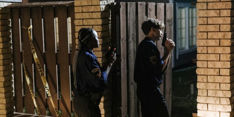 Law enforcement officers examining computers in a cryptocurrency fraud investigation.