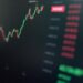 Financial graphs and digital currencies displayed on a screen, representing crypto investment.