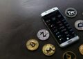 A smartphone displaying Jack Dorsey's Bitchat app with crypto symbols and regulatory logos.