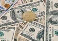 Digital currency symbols with a background of US dollar bills and a warning sign.
