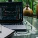 A person reviewing DeFi platforms on a laptop with financial charts and crypto symbols visible.