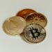 Coins and cryptocurrency symbols on a digital background with a fine notice overlay.