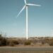Wind turbines surround a sprawling data center building in Texas, highlighting renewable energy use.