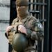 A U.S. soldier is handcuffed outside a military building, surrounded by police.