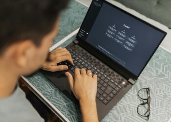 A developer using a laptop with blockchain graphics, showcasing Certik's AI Auditor tool.