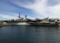 US Navy ships lined up off the coast, highlighting the oil supply disruption and price spike.