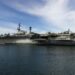 US Navy ships lined up off the coast, highlighting the oil supply disruption and price spike.