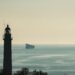 A cargo ship navigates the Strait of Hormuz, symbolizing maritime finance vulnerabilities.