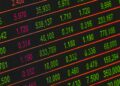 A stock market display board shows rising equity indices amid falling Brent crude oil prices.