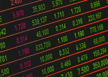 A stock market display board shows rising equity indices amid falling Brent crude oil prices.