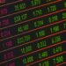 A stock market display board shows rising equity indices amid falling Brent crude oil prices.